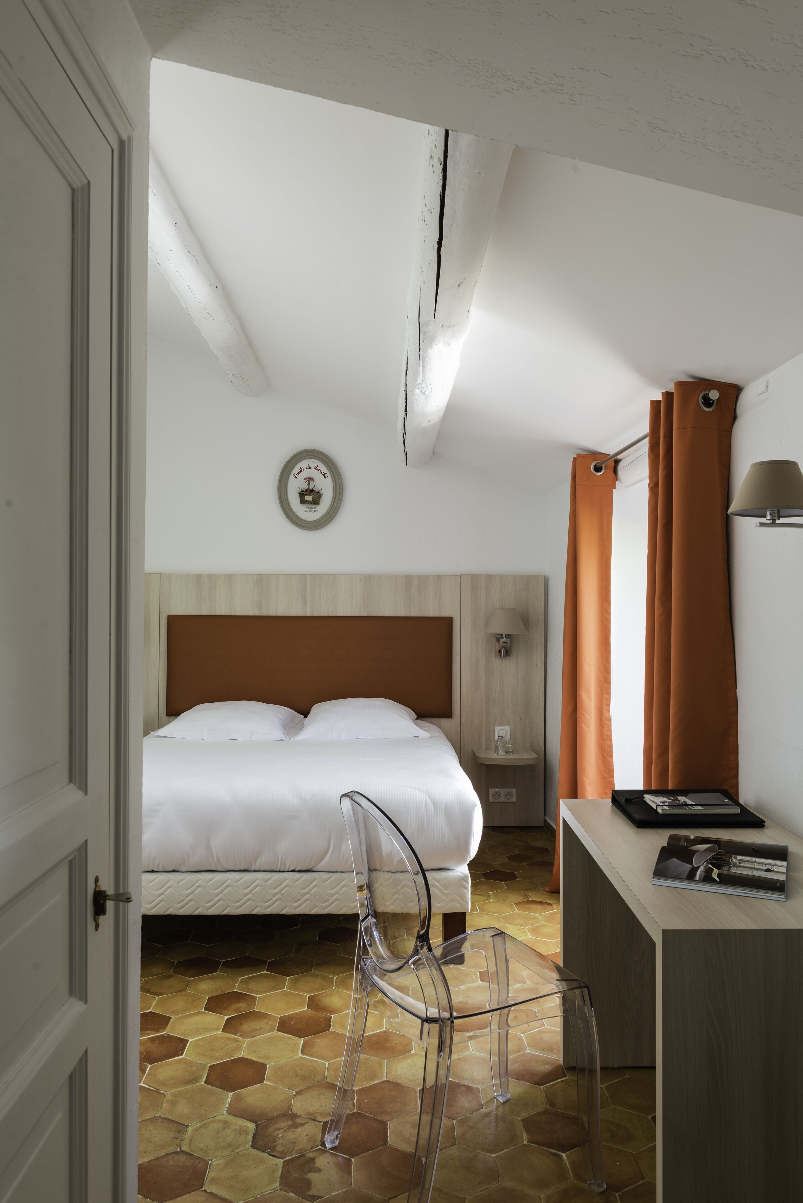 A bedroom with a bed, a desk, a chair, a nightstand, and a wall clock.