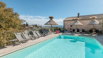 Relax by the pool surrounded by lush greenery and shaded seating.