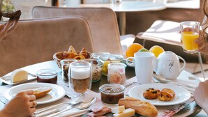 A breakfast table with various food items and drinks, set in a room with a view of the outdoors.