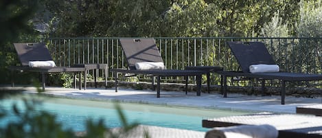 A poolside area with lounge chairs and a pergola.