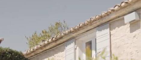Un edificio con techo de tejas y una ventana con cortina amarilla.
