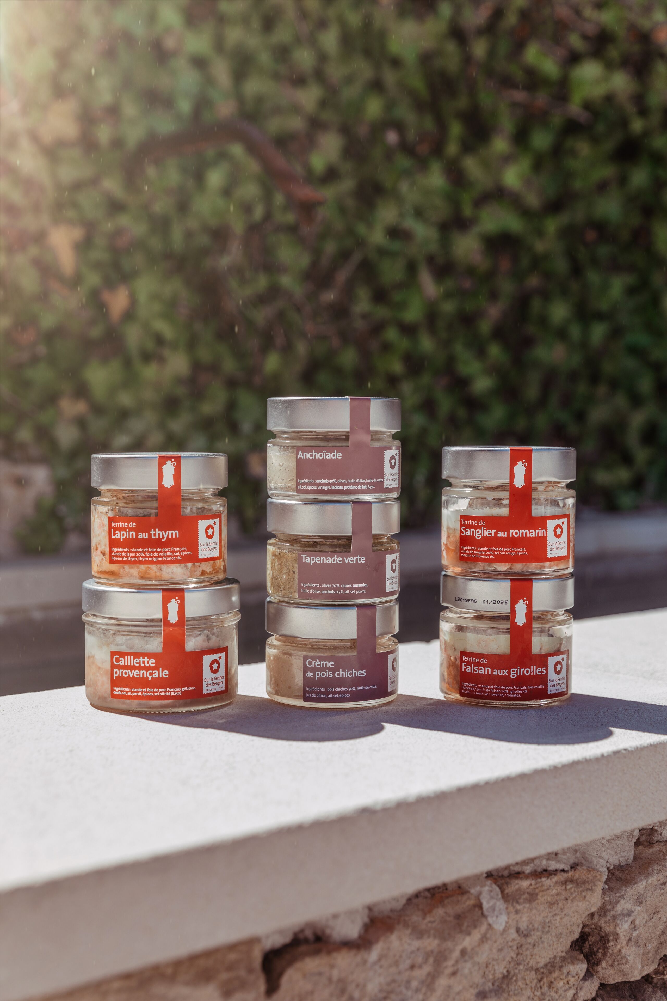 Three jars of food products on a ledge with a blurred green background.