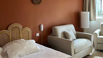 Una habitación de hotel con cama, sofá, lámpara y un reloj de pared.