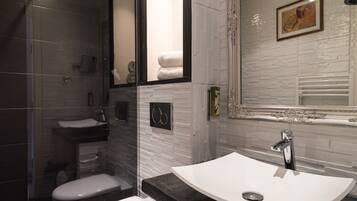 A modern bathroom with a glass-enclosed shower, a white sink with a black countertop, and a large mirror.