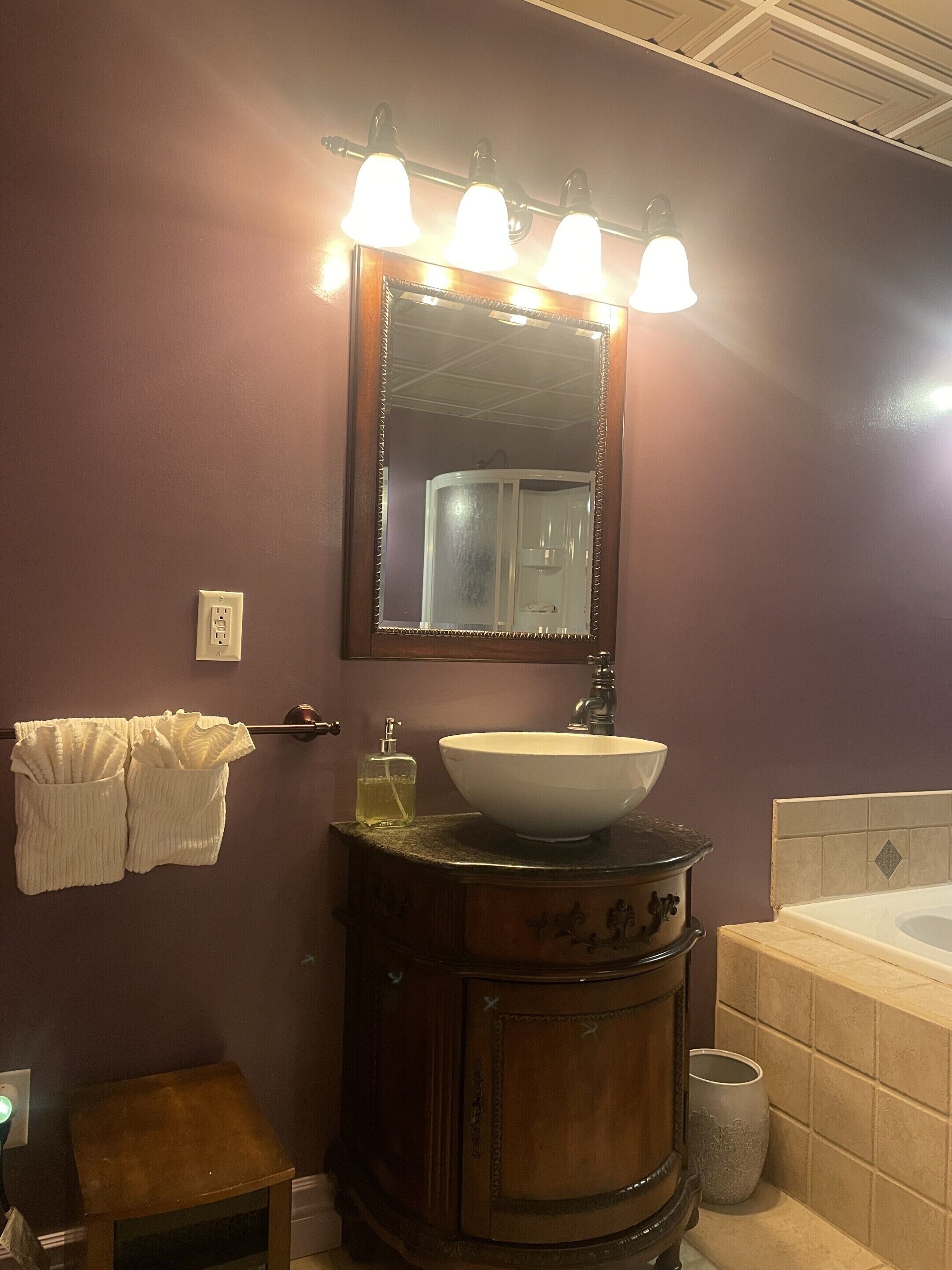 A bathroom with a vanity, a sink, a mirror, and a bathtub.