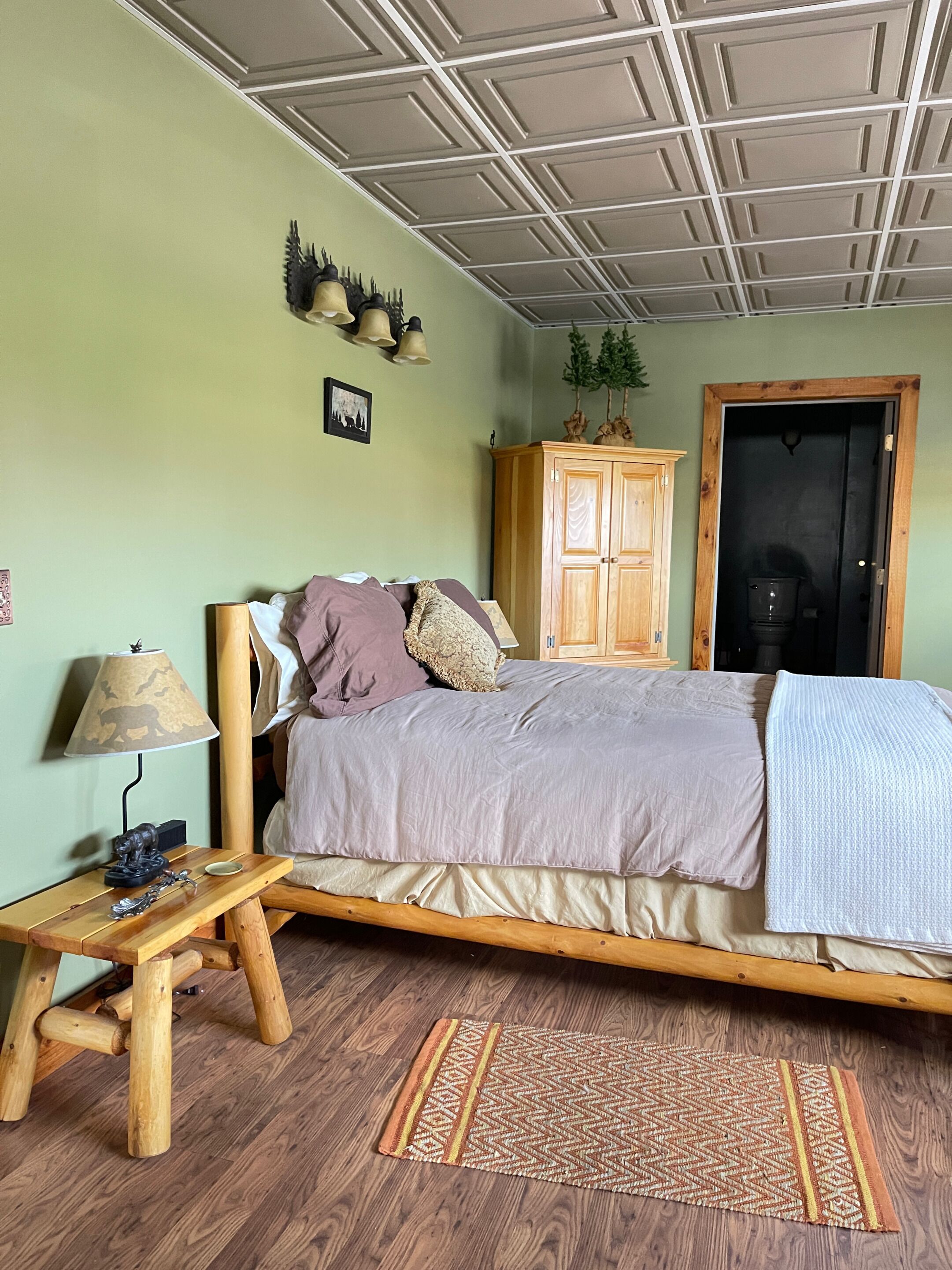 A bedroom with a bed, wooden nightstand, lamp, and a wardrobe.