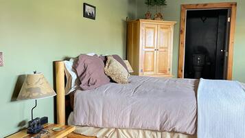 A bedroom with a bed, wooden nightstand, lamp, and a wardrobe.