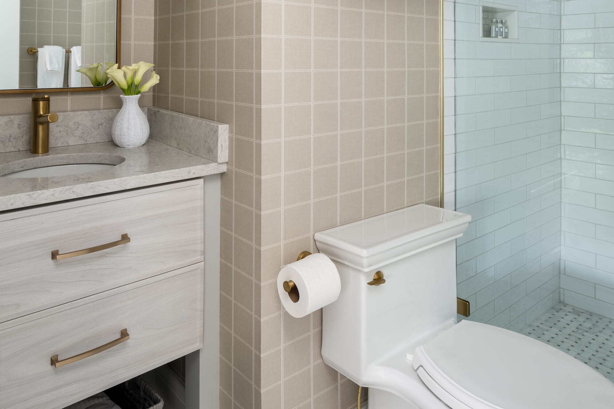 A bathroom with a toilet, a sink with a vase of flowers, and a shower area.
