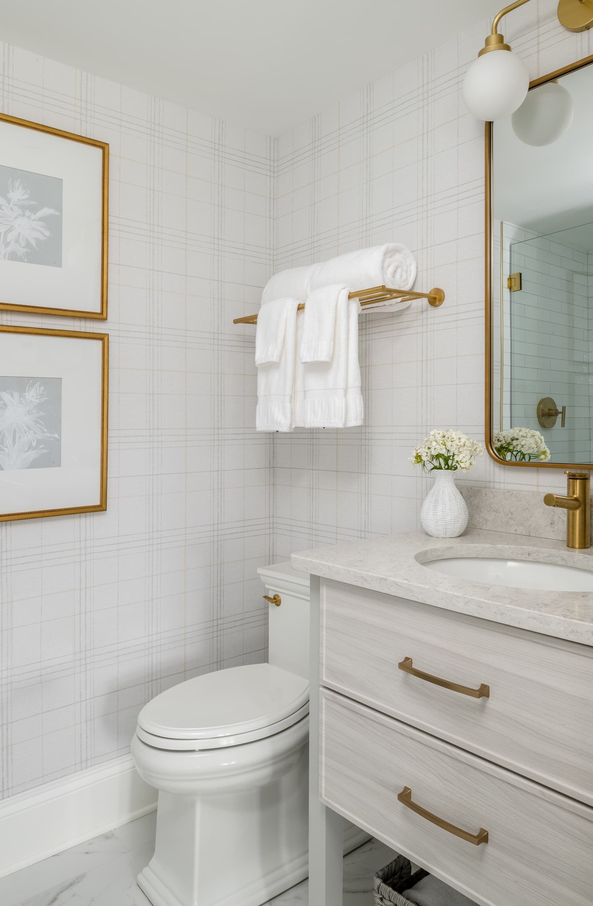 A bathroom with a white toilet, a vanity with a gold faucet, and a mirror with a gold frame.