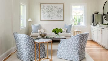 A living room with a sofa, two armchairs, a coffee table, and a painting on the wall.