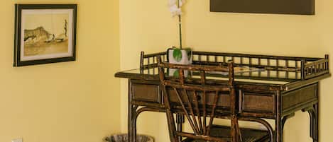 A dining area with a table, chairs, a framed picture, a mirror, and a potted orchid.
