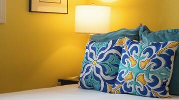 A hotel room with a bed, a framed picture on the wall, and a bedside lamp.