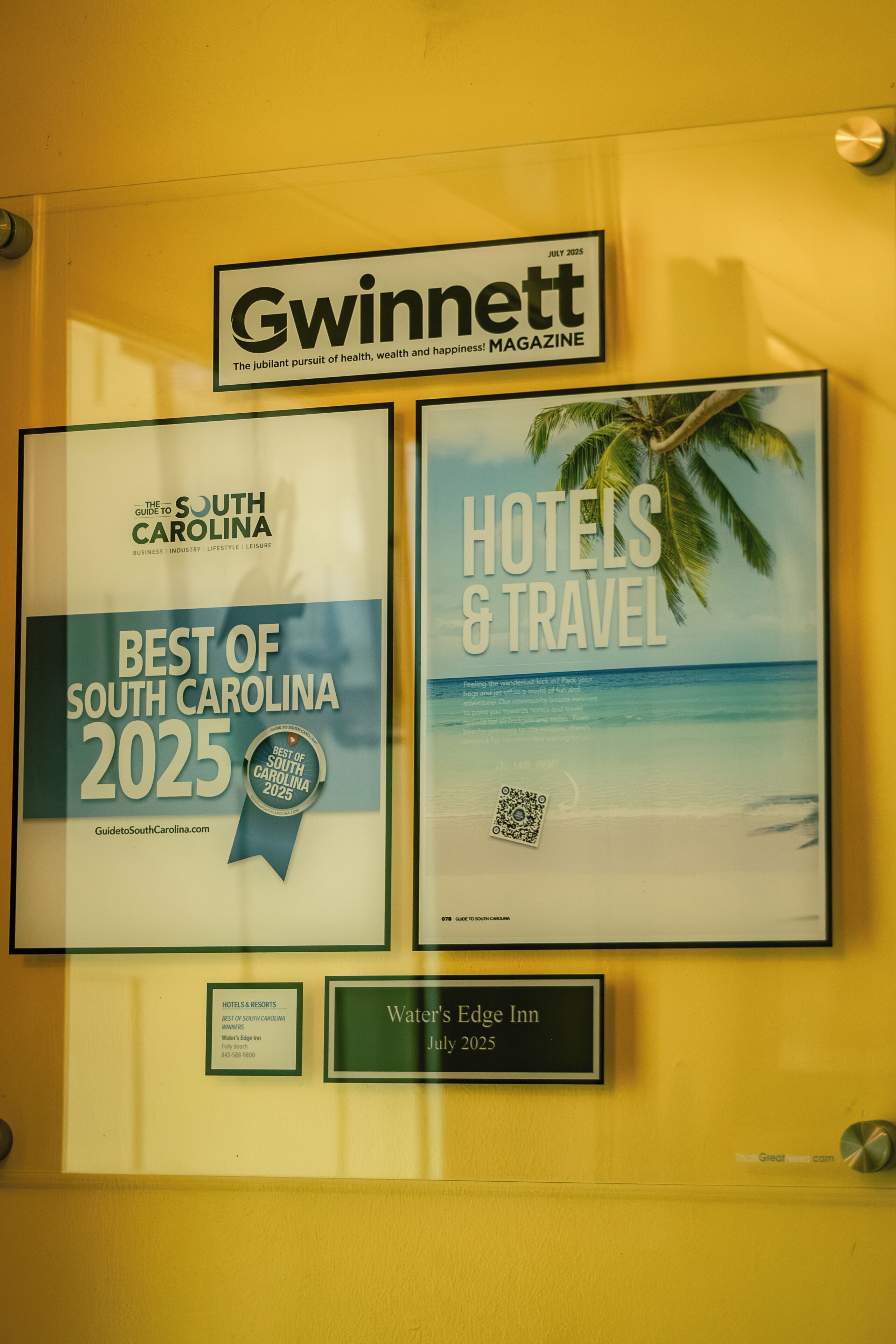 Deux prix encadrés, l’un récompensant le « meilleur de la Caroline du Sud 2025 » et l’autre récompensant les « hôtels et le tourisme », décernés par le magazine Gwinnett, comprenant un code QR et une plaque commémorative pour l’établissement Water's Edge Inn.