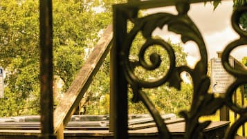 A wrought iron gate with a wooden structure behind it, a sign with text, and a view of trees.