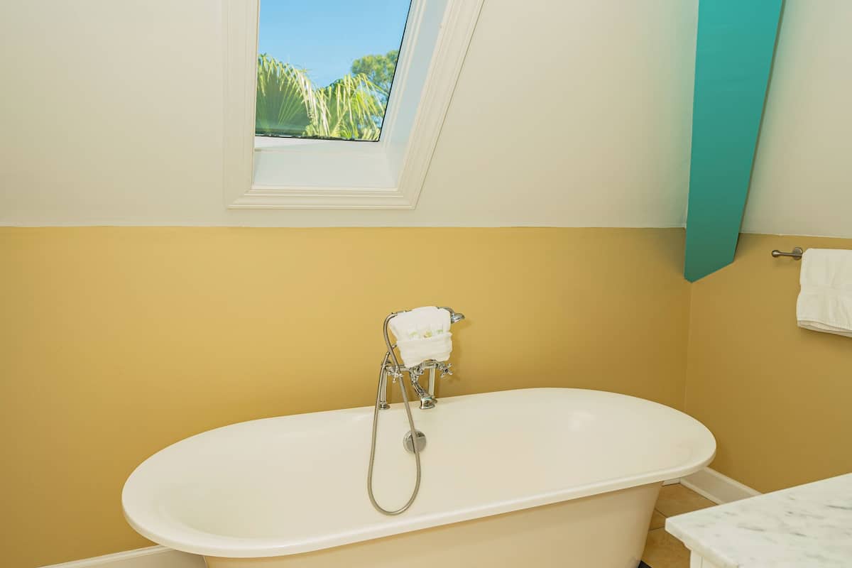 A bathroom with a freestanding bathtub, a window with a view, and a tiled floor.