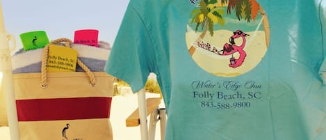 Una sombrilla en la playa con una toalla y un bolso de playa sobre una silla.