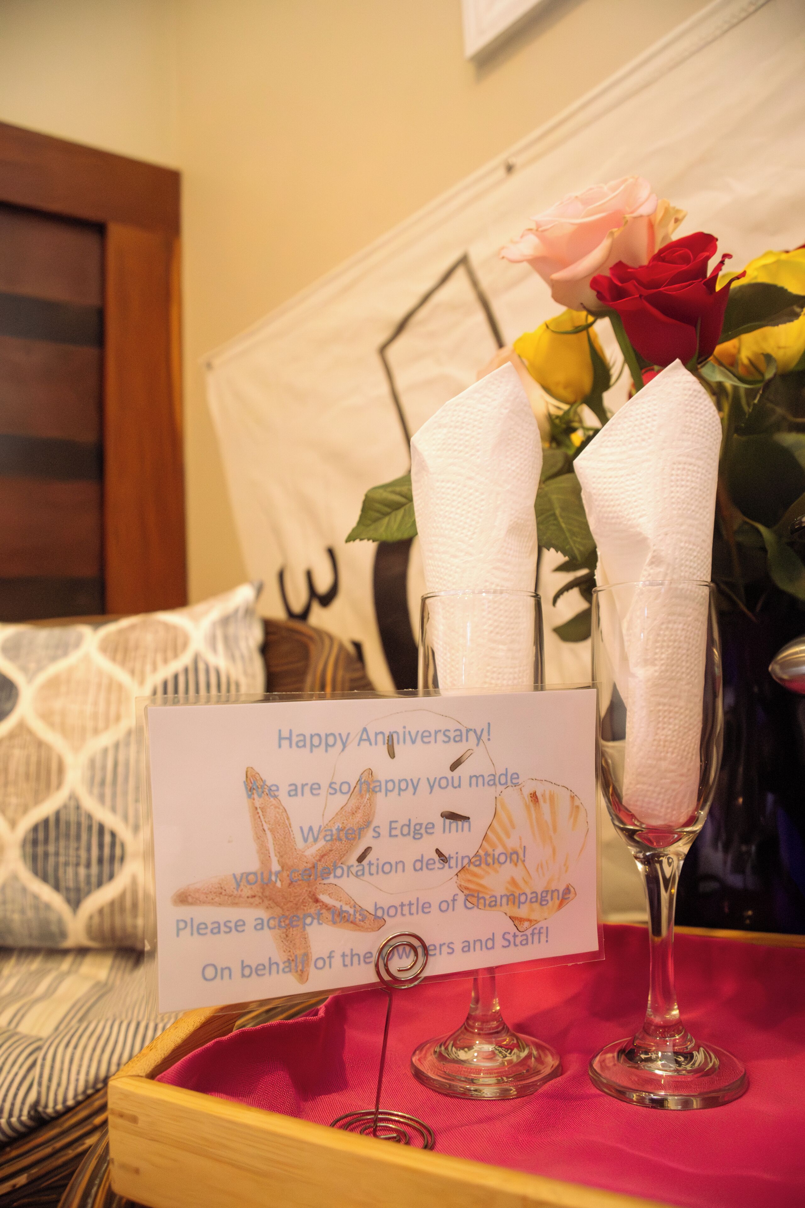 A table with a card, two glasses, and a bouquet of flowers.