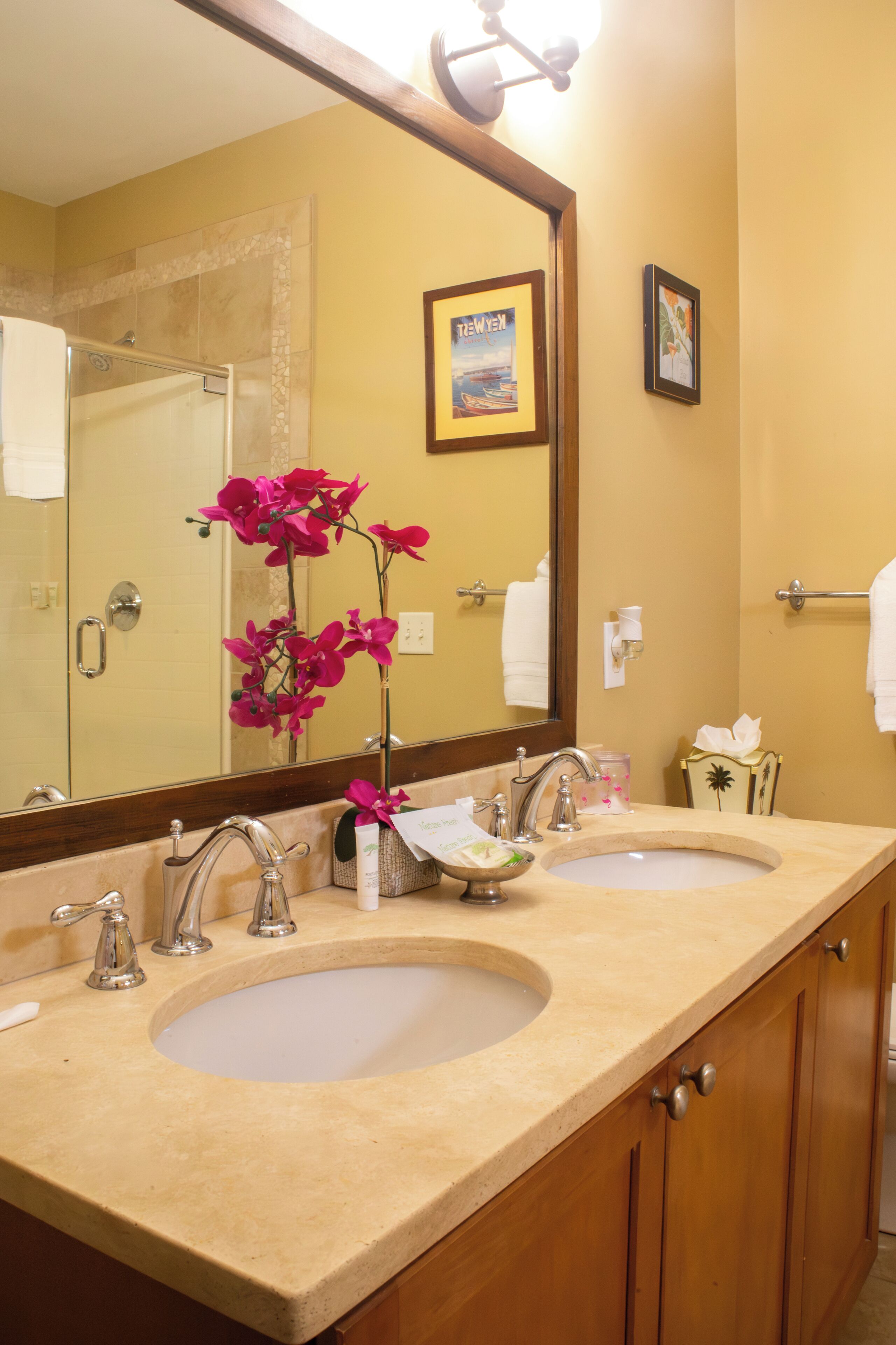 A bathroom with two sinks, a large mirror, and a framed picture on the wall.