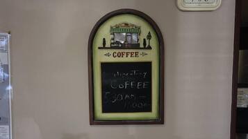 A coffee shop counter with a Bunn coffee maker, a chalkboard menu, and a clock on the wall.