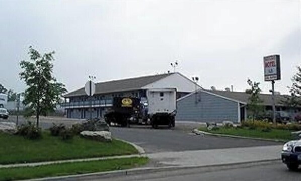 A building with a large truck parked in front, a signboard, and a road. - Mayflower Motel Milford (Milford)