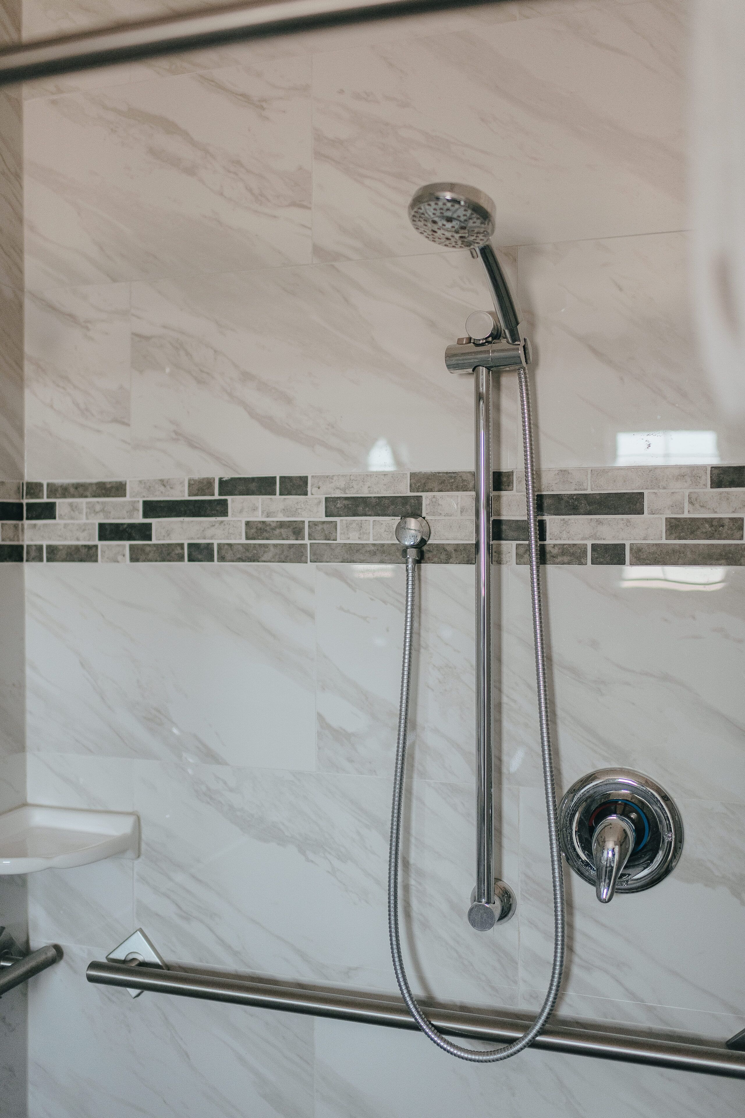 A shower with a handheld showerhead and a wall-mounted faucet.