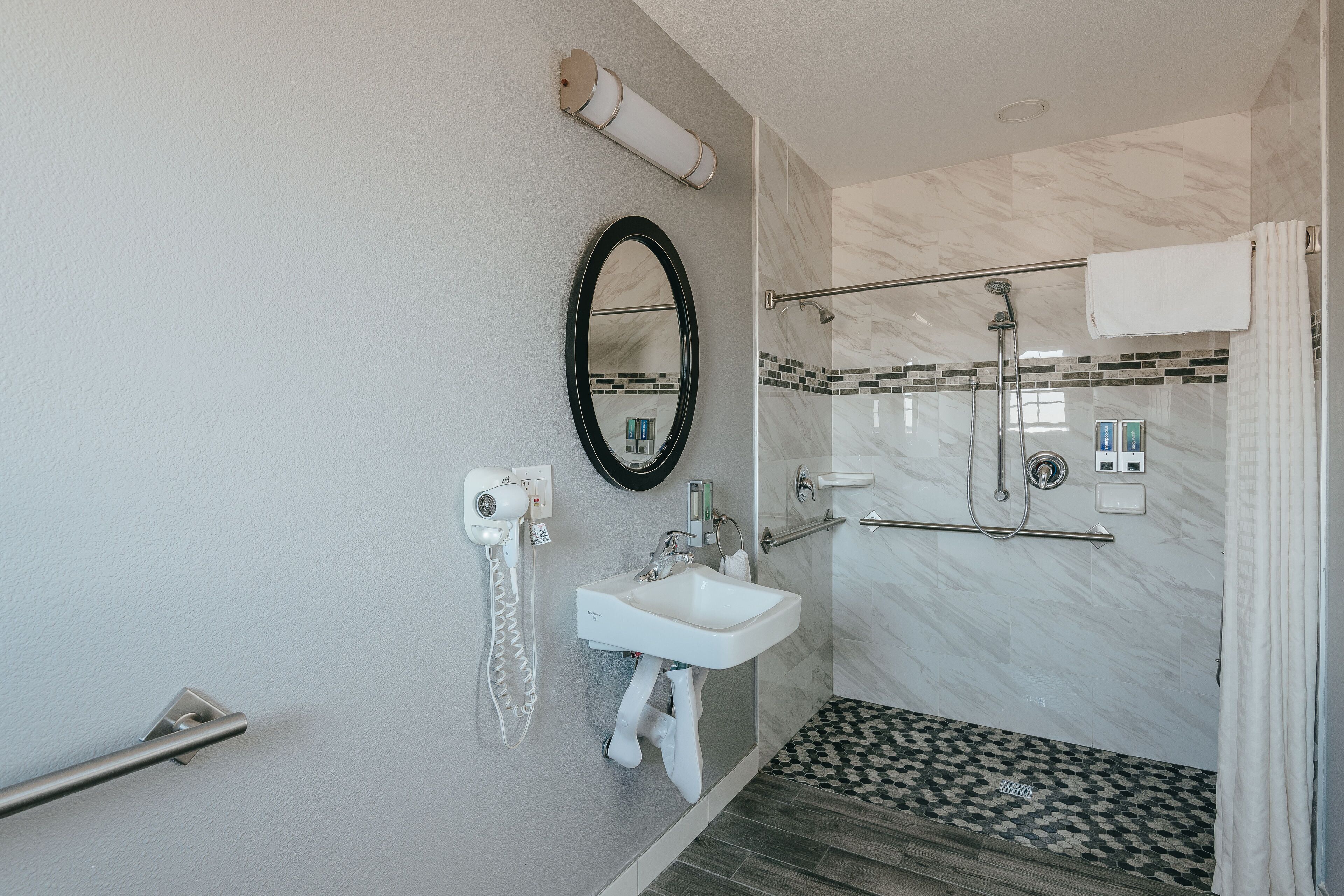 A bathroom with a white sink, a mirror, a towel rack, a shower area, and a toilet.