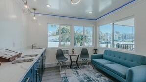 Een moderne keuken met een groot raam, een blauwe bank en een eethoek met twee stoelen.