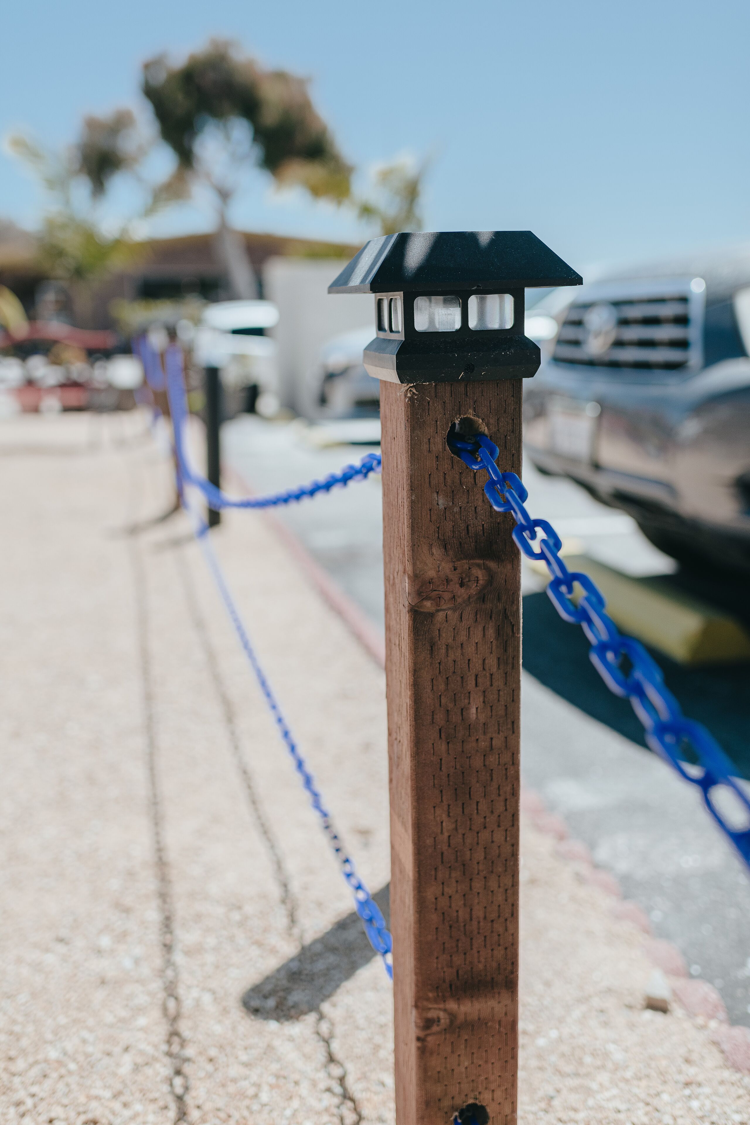 A wooden post with a black top and blue chain.