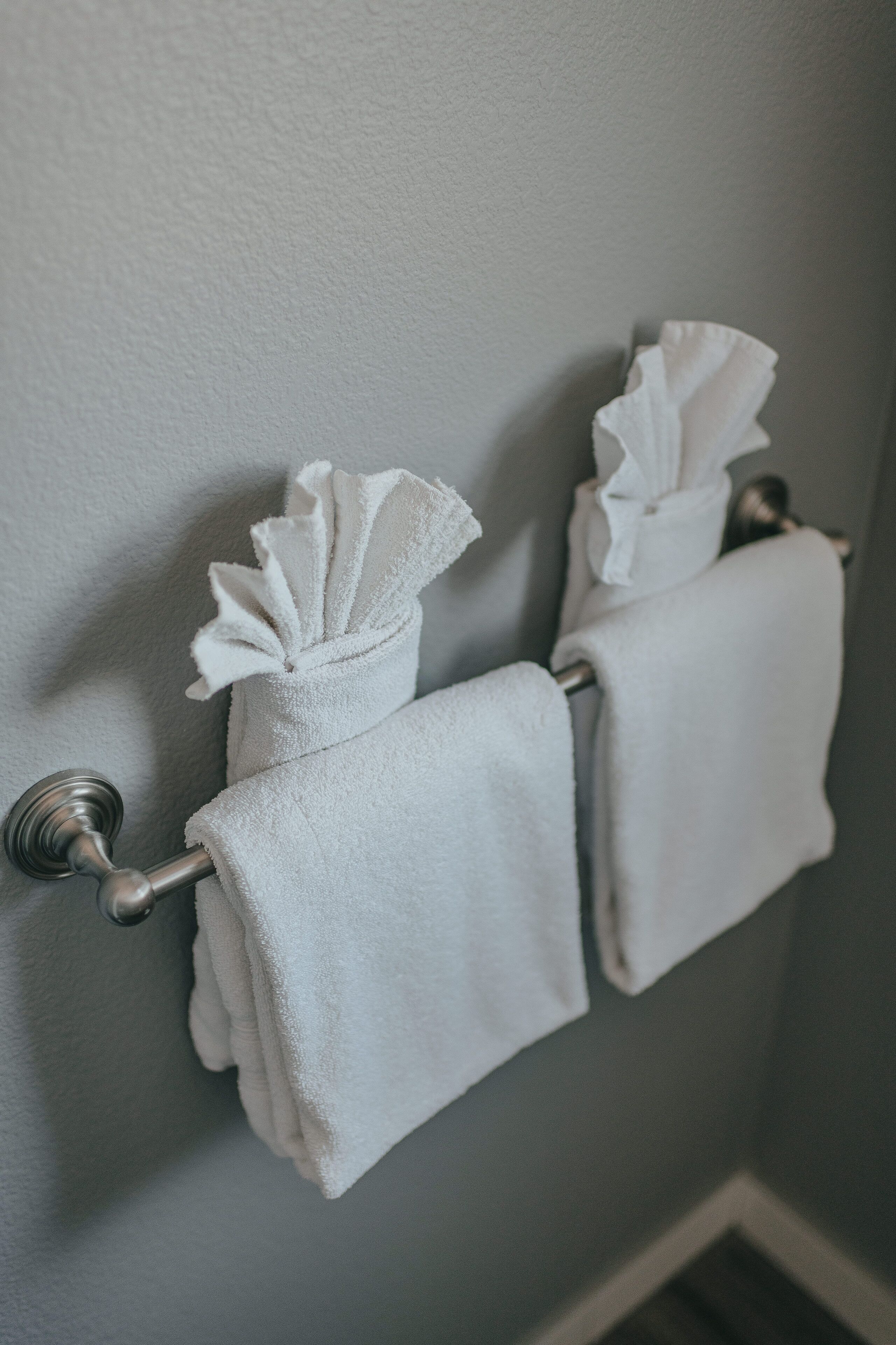 Une salle de bain avec deux serviettes blanches suspendues à un porte-serviettes fixé au mur.