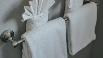 Une salle de bain avec deux serviettes blanches suspendues à un porte-serviettes fixé au mur.