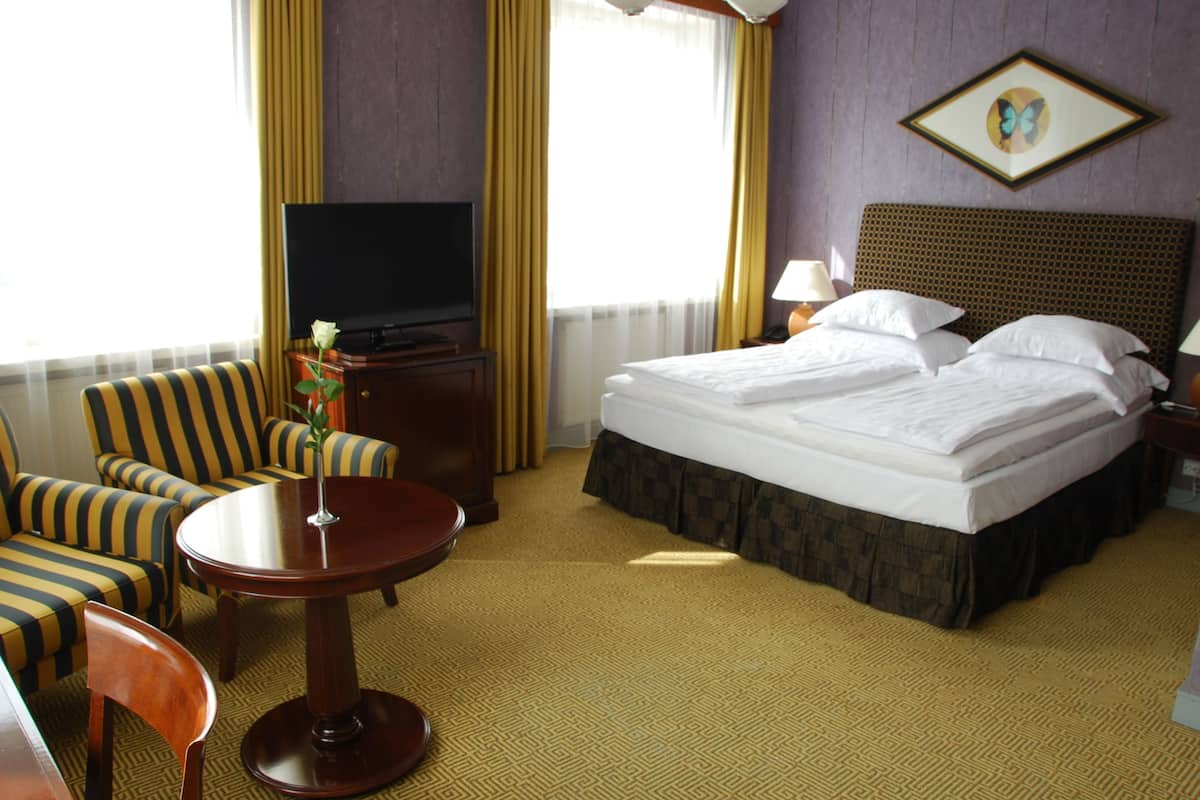 Ein Hotelzimmer mit Bett, Fernseher, Schreibtisch und Stuhl.