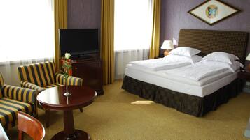 Una habitación de hotel con cama, televisión, escritorio y silla.