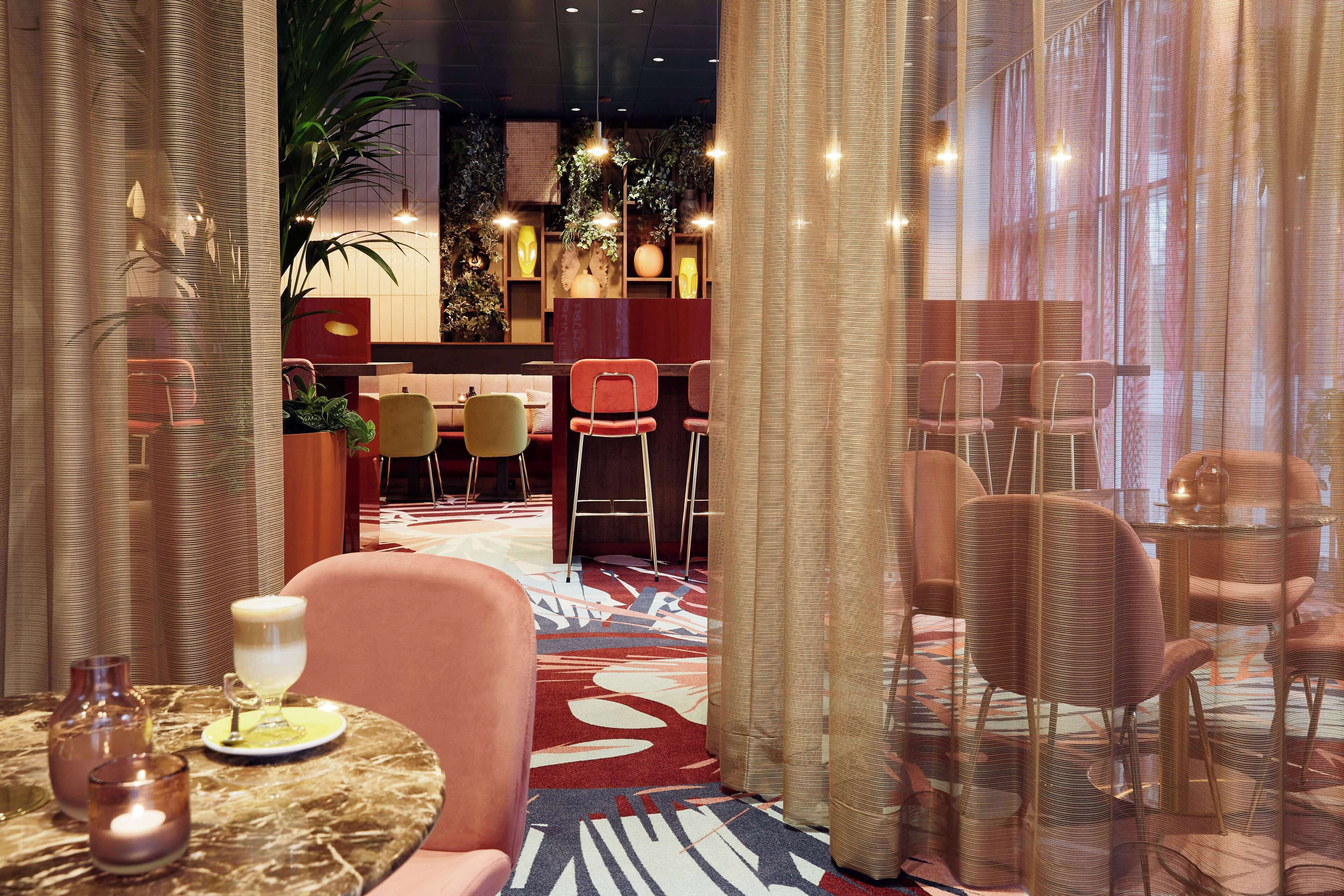 Een hotel lobby met een centrale zithoek, een receptiebalie en een plant.