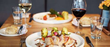 Una mesa de comedor con platos de comida, copas de vino y cubiertos.