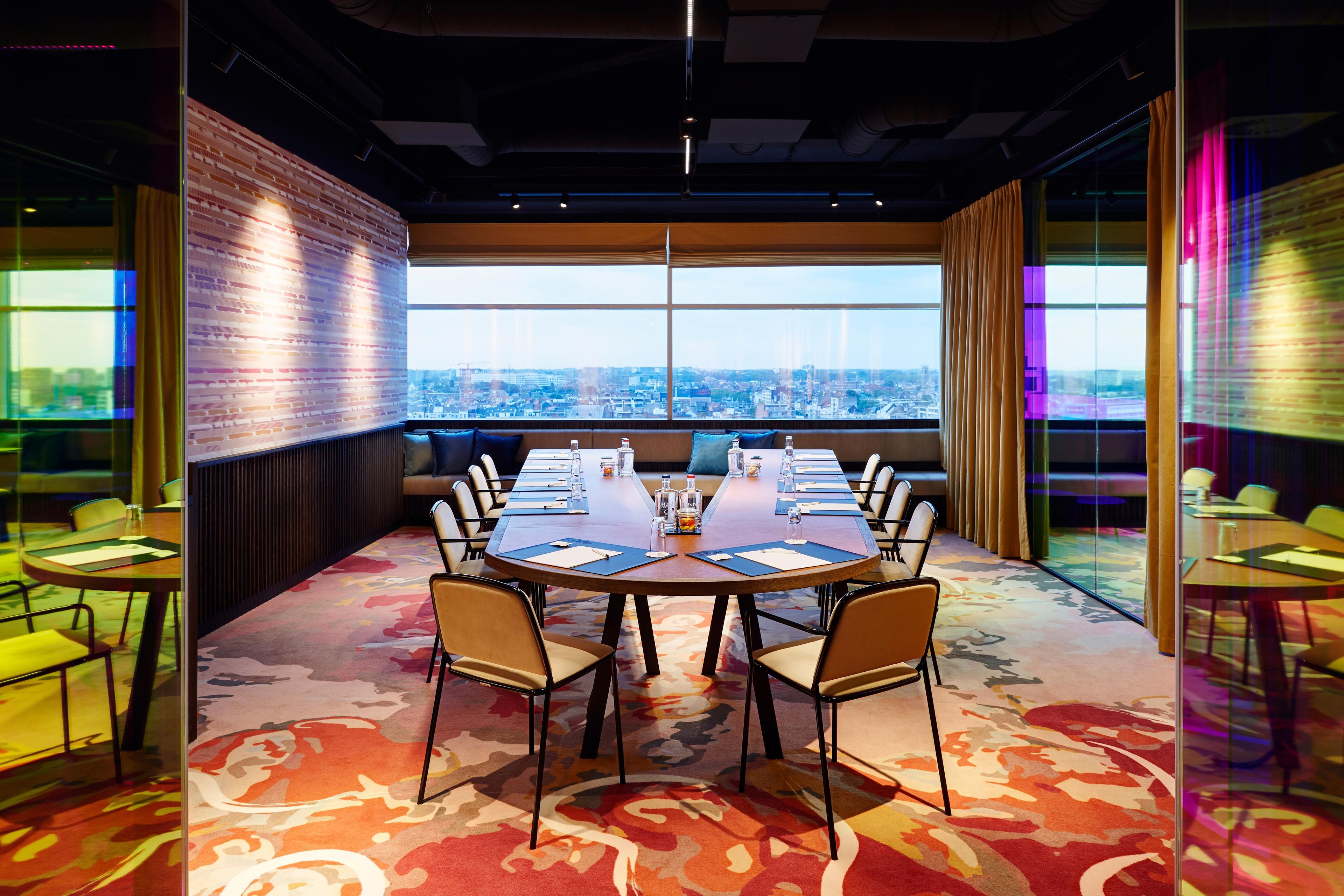 A conference room with a large table, chairs, and a city view through large windows.