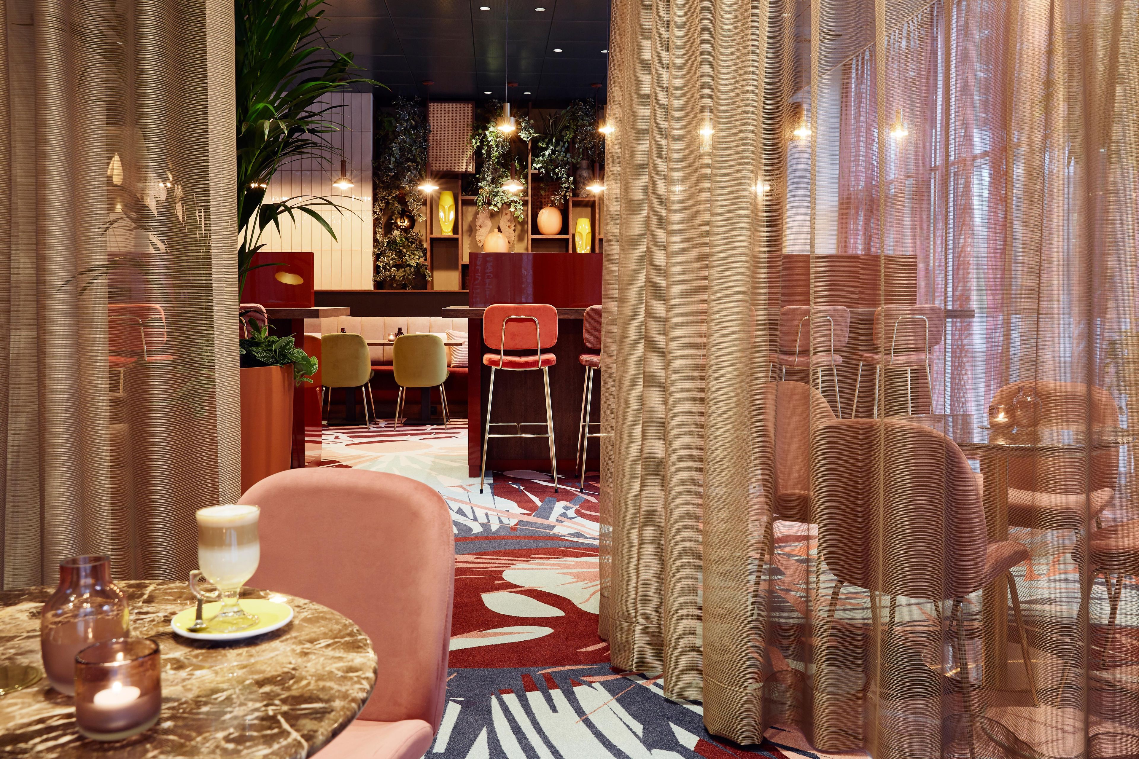Un restaurant doté d’un bar, de tables et d’une moquette à motifs.