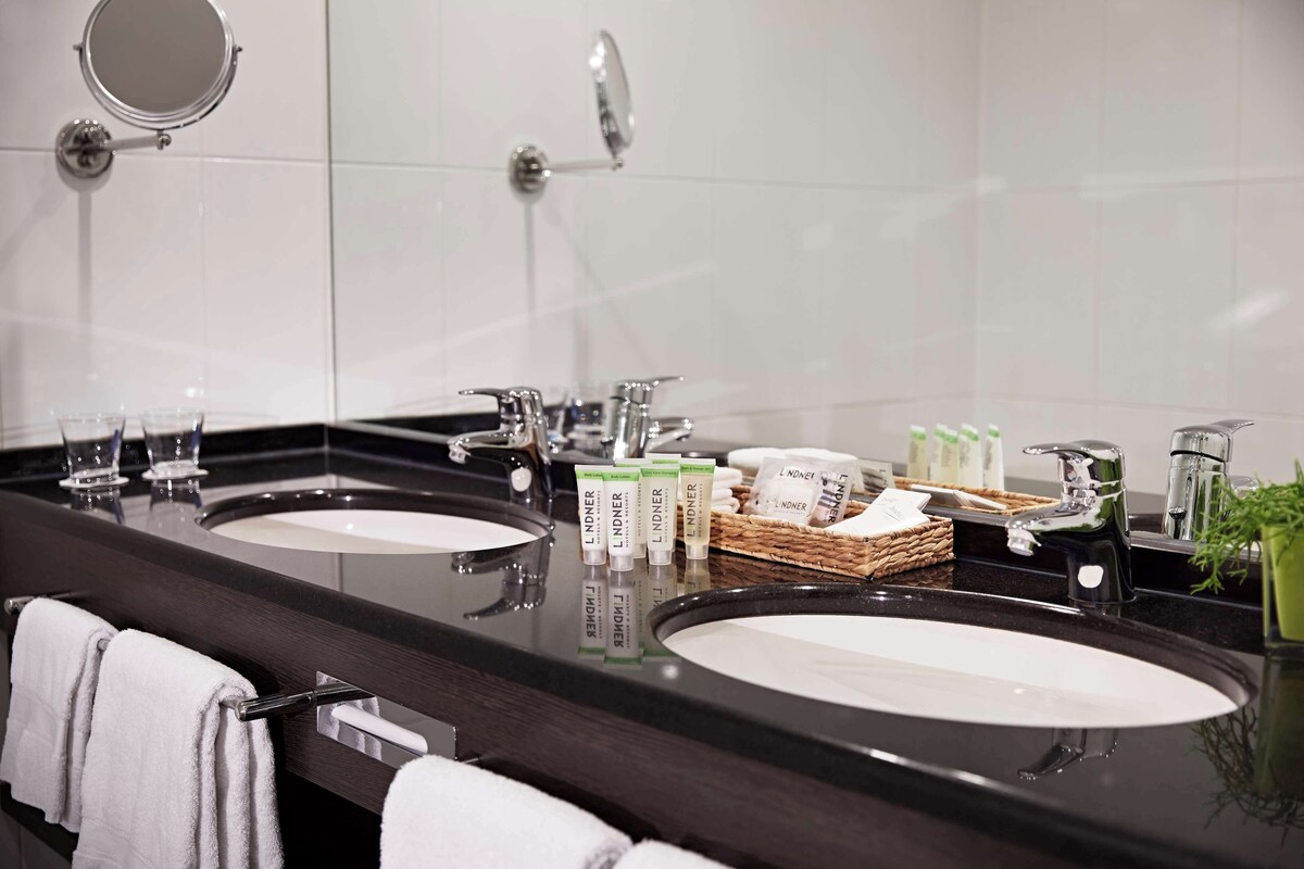 A modern bathroom with two sinks, a mirror, and toiletries.