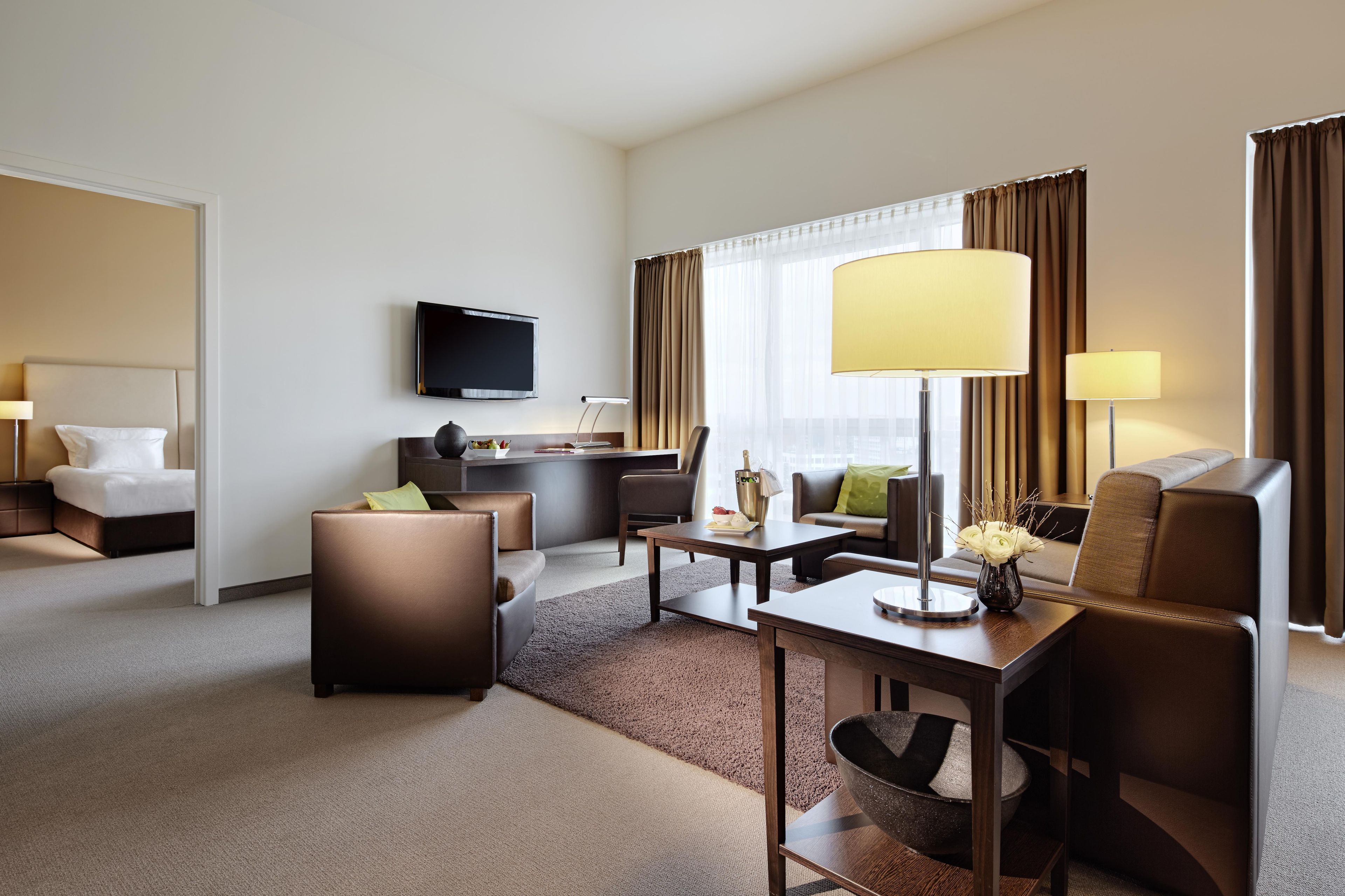 Una habitación de hotel con una cama, un escritorio, un televisor, un sofá y una mesa de centro.