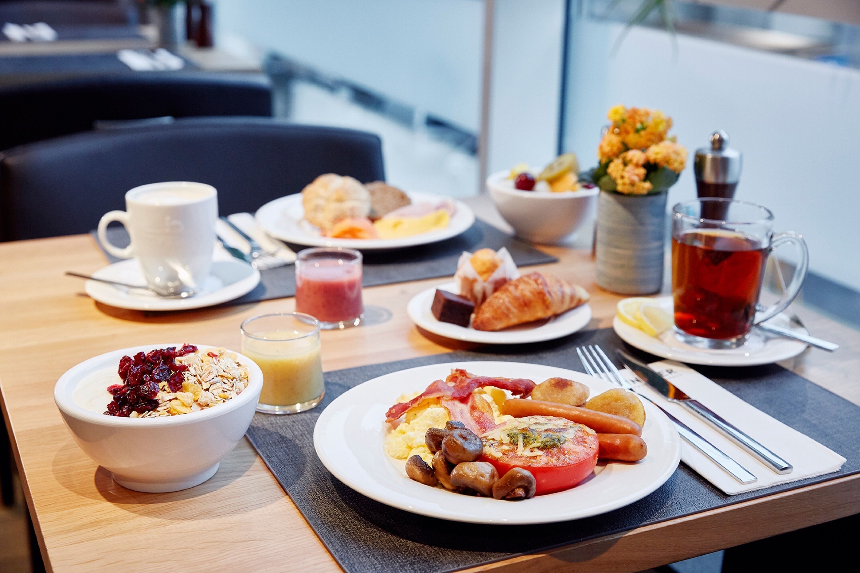 Una mesa de desayuno con diversos platos, incluyendo cereal, huevos, tocino y tostadas.