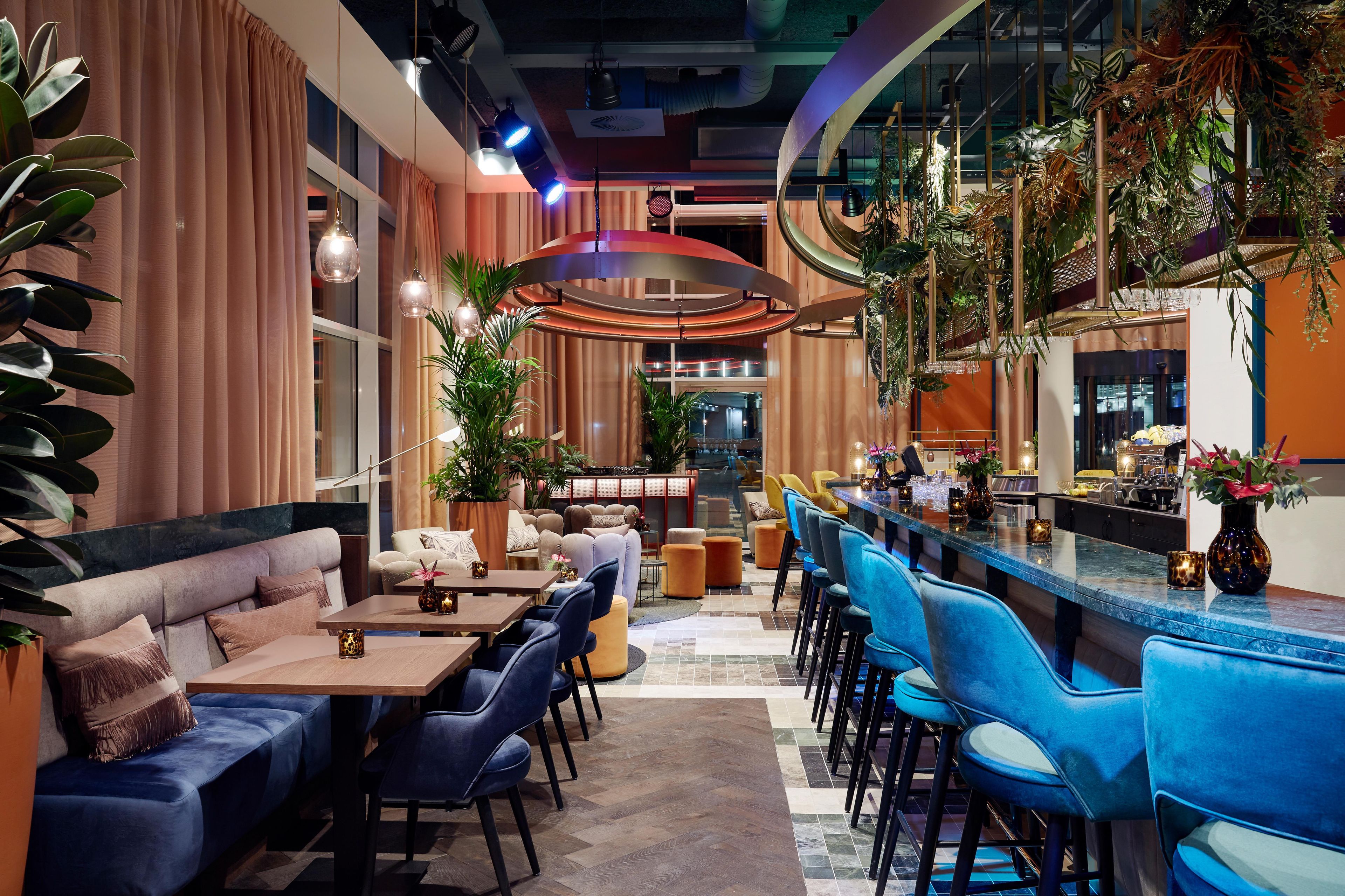 A modern bar area with seating, bar counter, and ambient lighting.