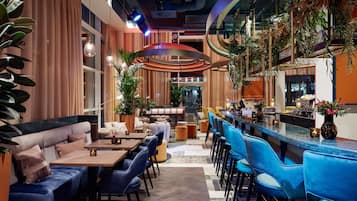 A modern bar area with seating, bar counter, and ambient lighting.