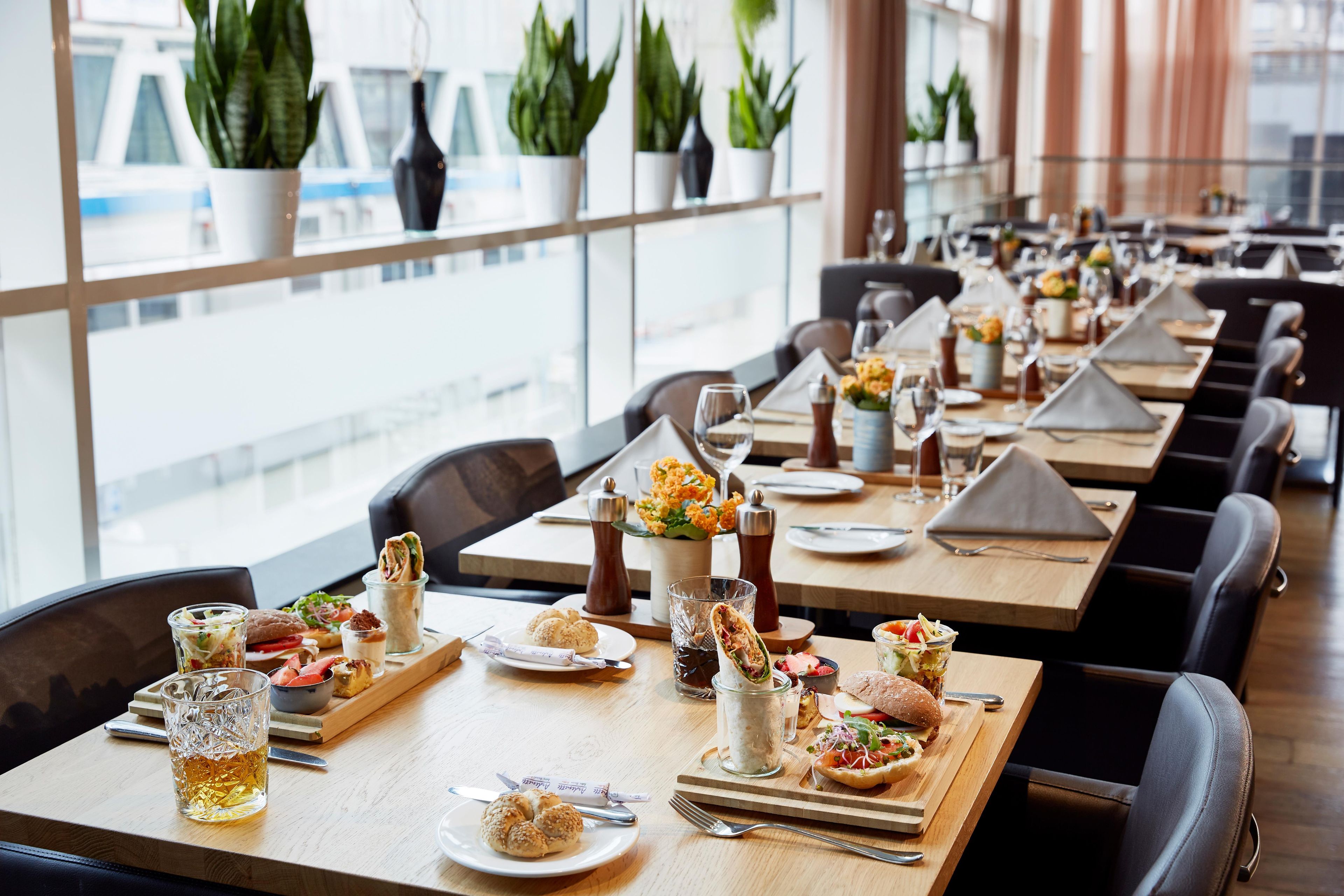 A restaurant with multiple tables set for dining, each with plates, cutlery, and drinks.