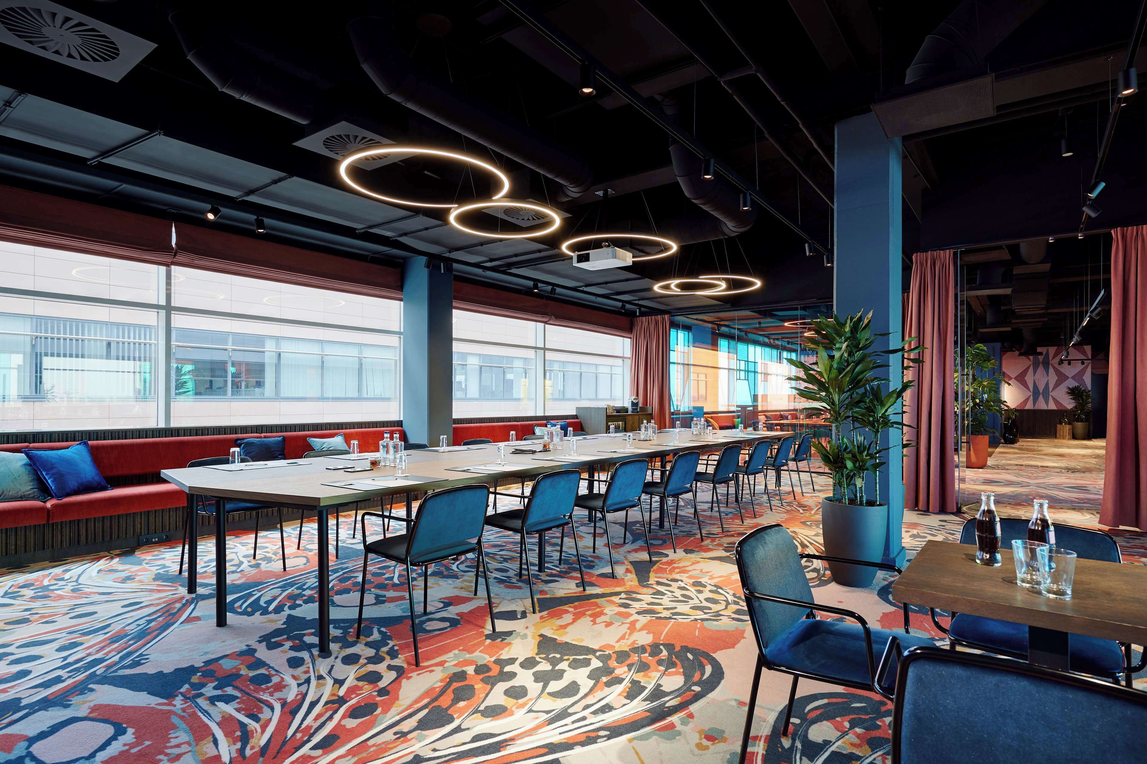 A conference room with a long table, blue chairs, and a patterned carpet.