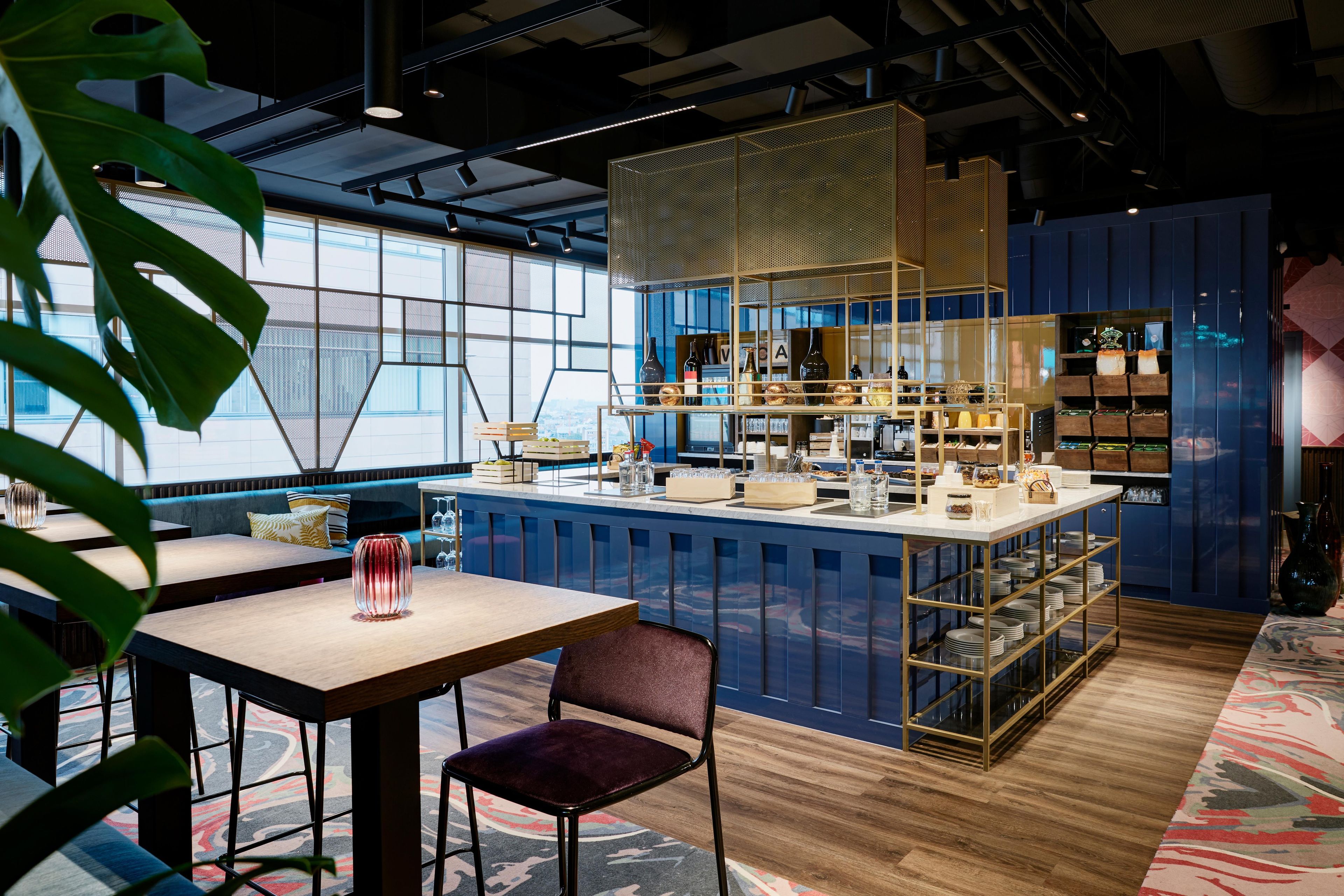 A modern bar area with a bar counter, seating, and a view through large windows.
