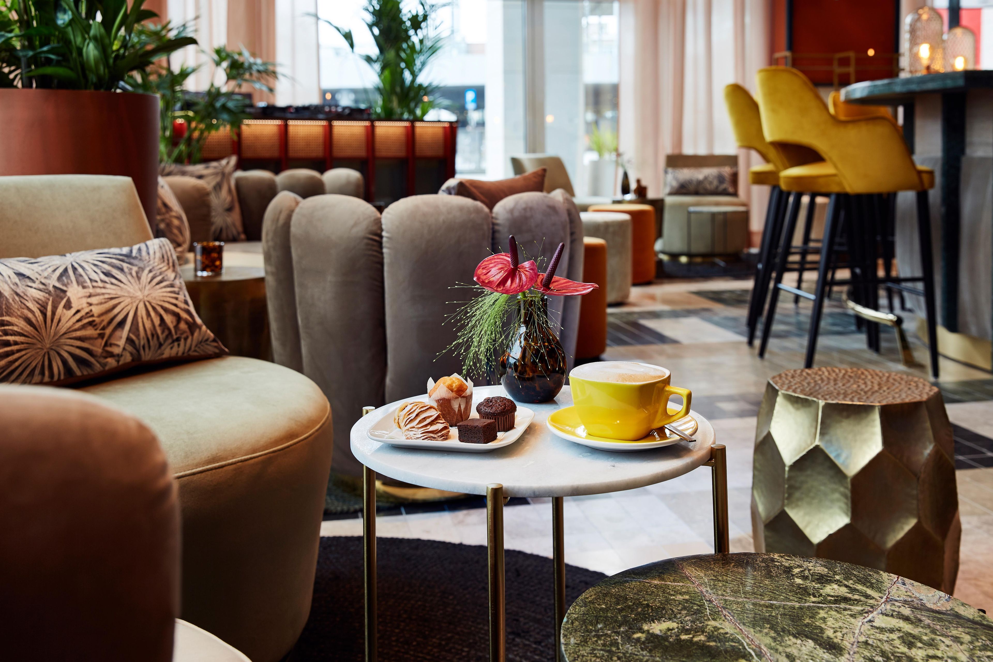 Un espace de détente moderne avec des canapés, une table basse et un coin bar doté de chaises jaunes.
