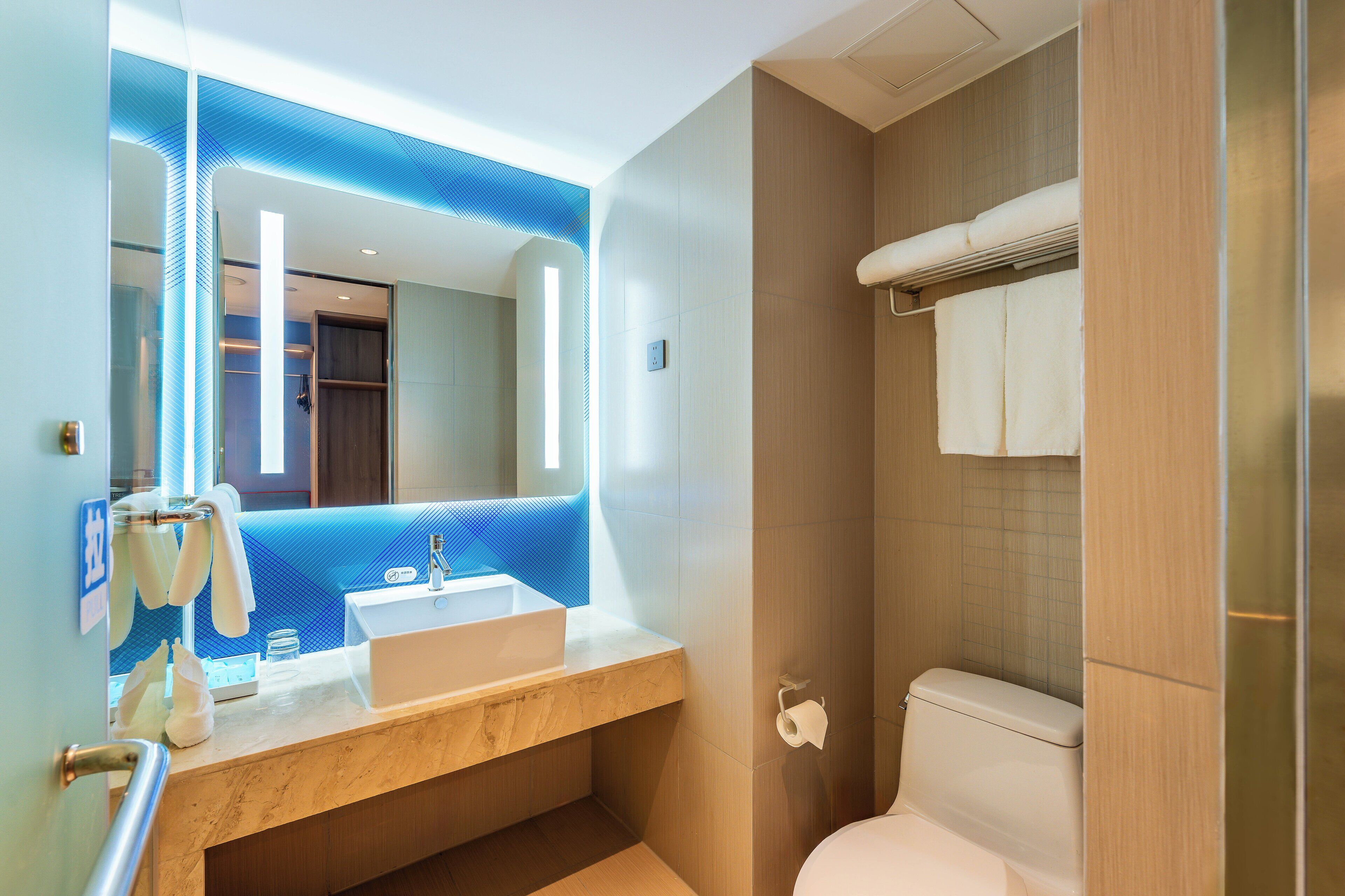 A modern bathroom with a sink, mirror, and toilet.