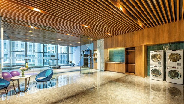 A modern hotel lobby with a large glass wall, a fitness area, and a laundry facility. - Holiday Inn Express Hefei South by IHG (Hefei)