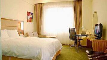Une chambre d’hôtel avec un grand lit, un bureau avec un ordinateur, une télévision et une chaise.