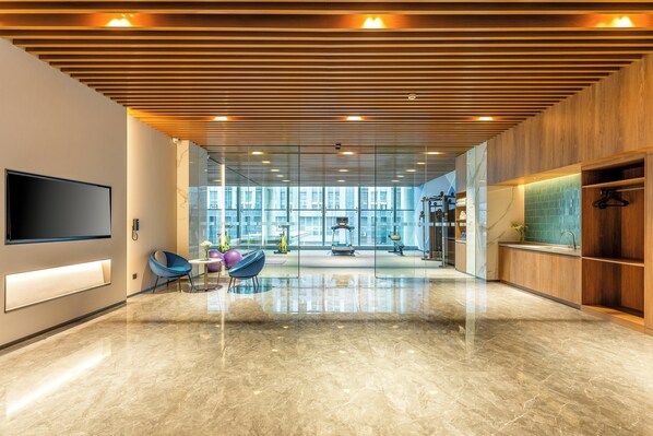 A spacious lobby with a large TV, exercise equipment, and a modern design.