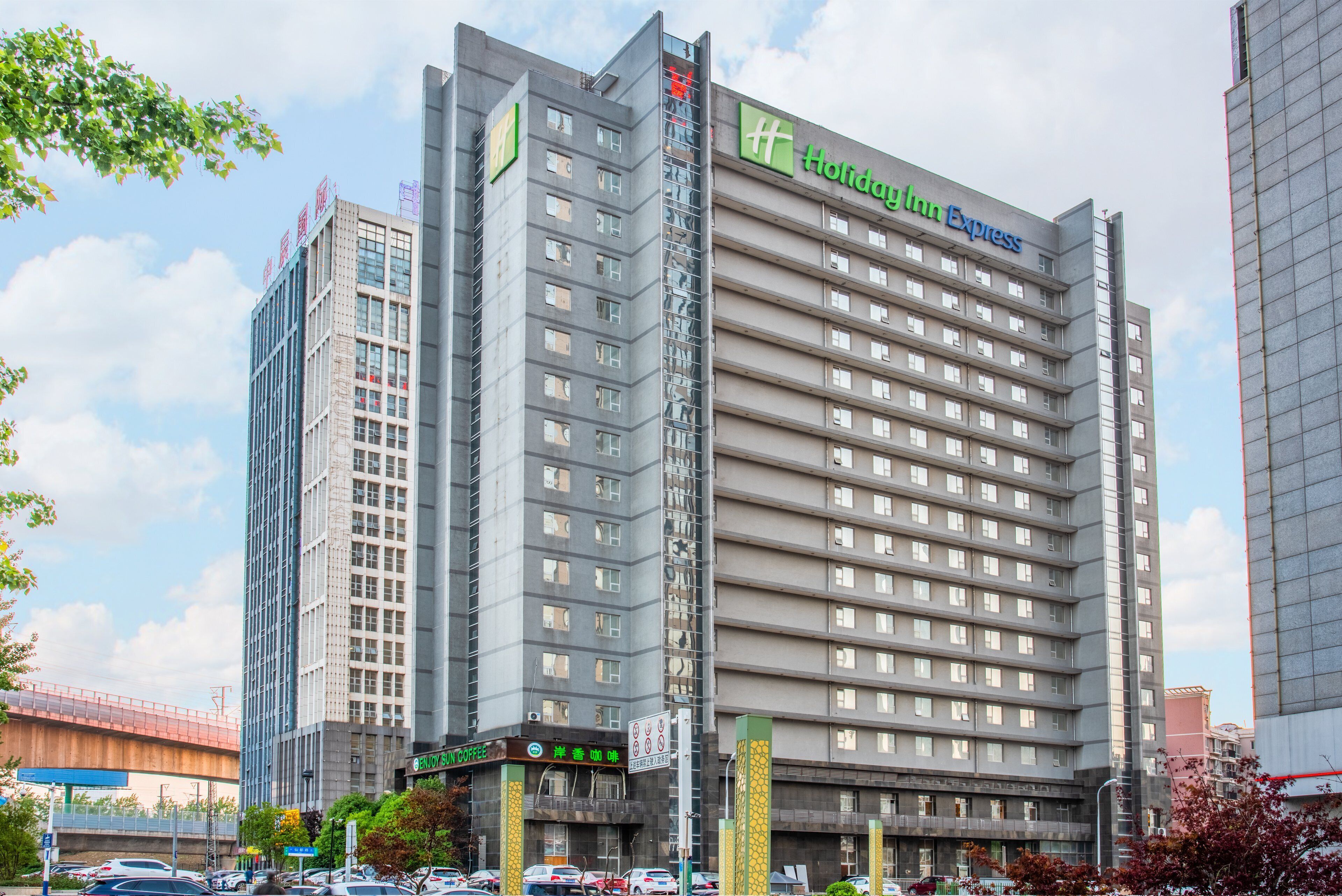 Un hotel de varios pisos con un llamativo letrero de Holiday Inn Express, una cafetería y un estacionamiento.
